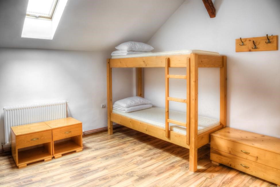 empty dorm room with a bunk bed, two bedside tables, and a small dresser
