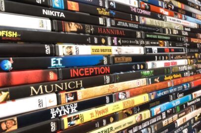A large stack of DVDs on a storage shelf.