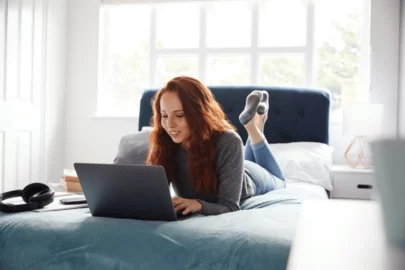 College student on laptop in dorm room.