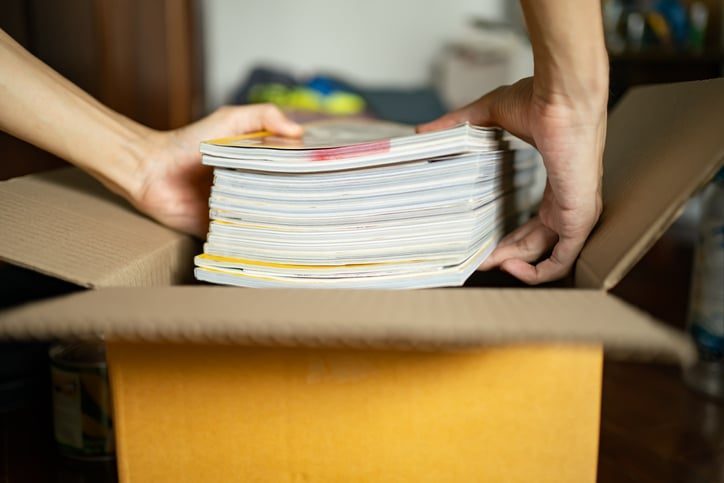 A woman putting books into a box for storage.