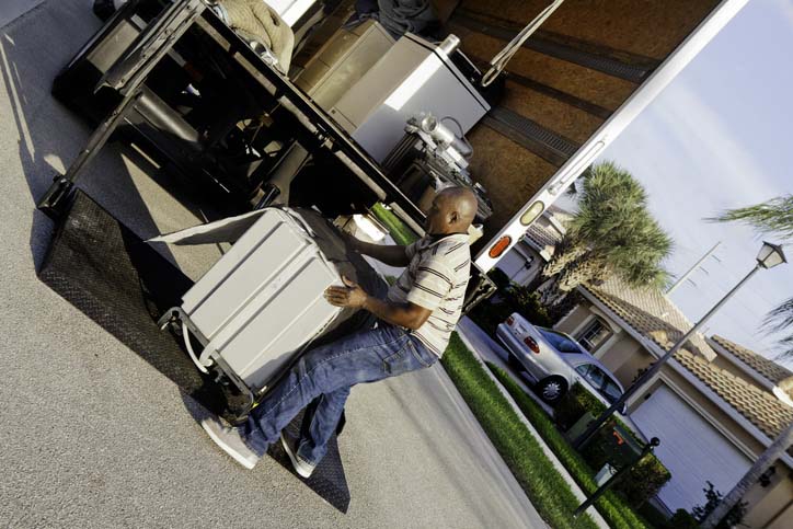 A man loading a household appliance into a moving truck.