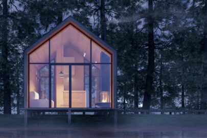 A small home in the woods with a lot of windows.