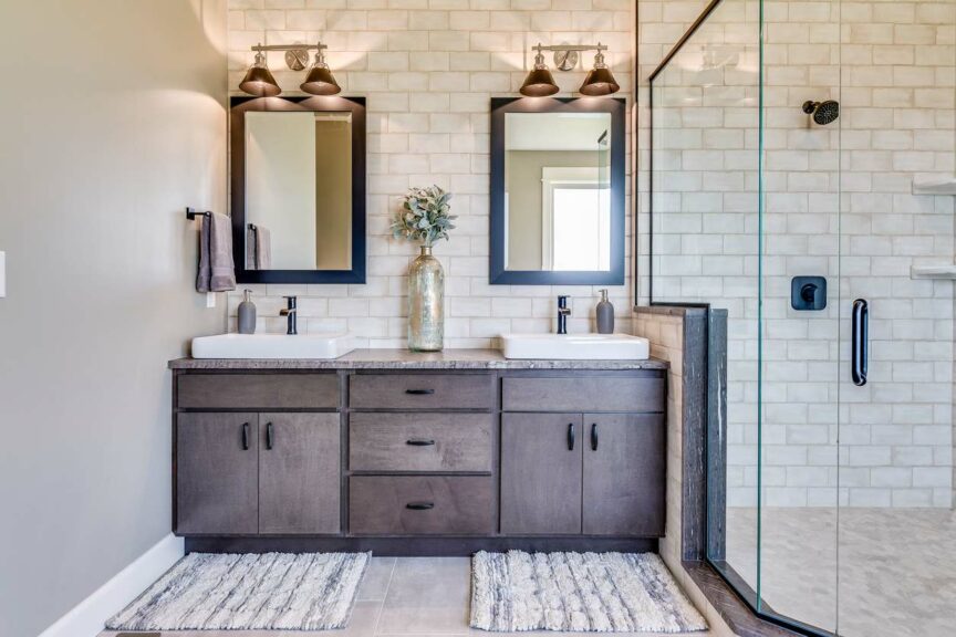 A modern-looking bathroom with a double vanity and a glass-doored shower