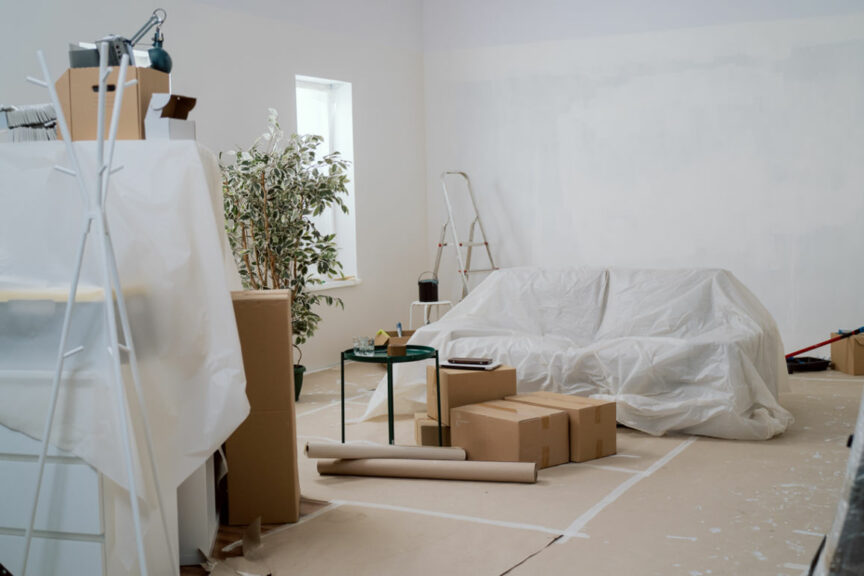 A room prepped for painting with paper on the floor and furniture covered.