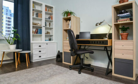 Desk and shelving units against the wall of a small room.