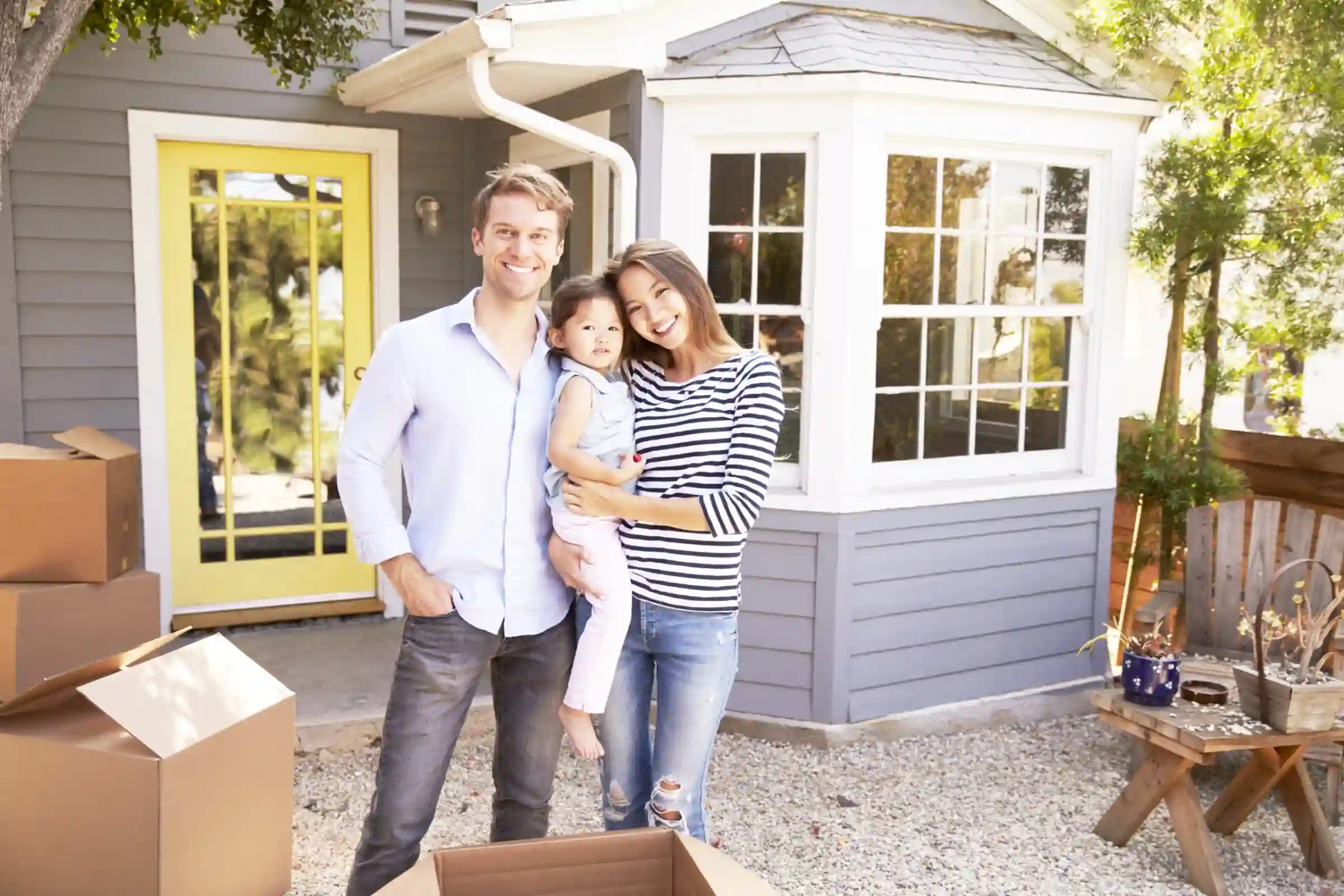 Portrait Of Excited Family Standing Outside New Home.