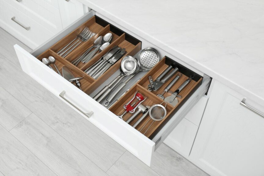 A view of an open drawer in a kitchen with differently organized utensils and cutlery.