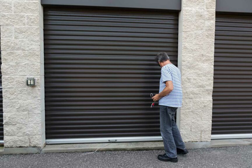 A senior male using a key to open a lock at his self storage unit.